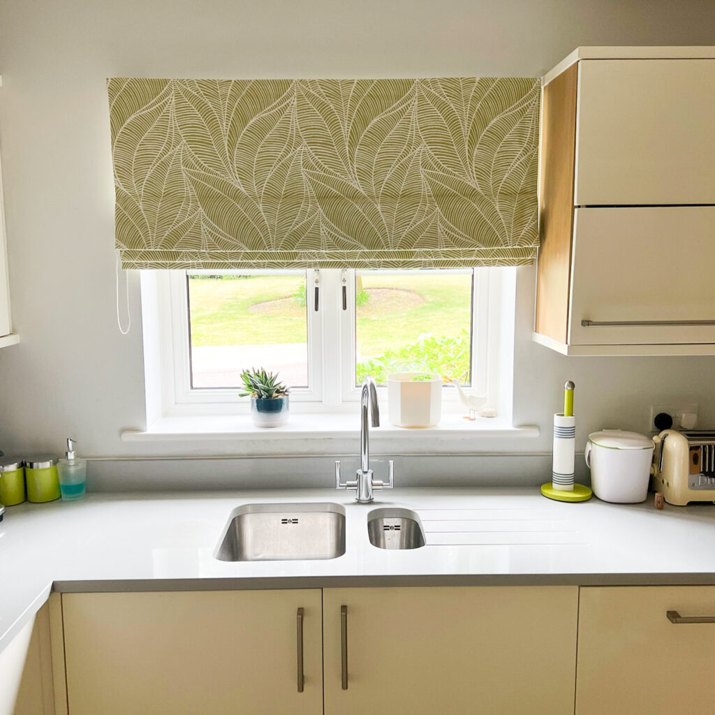 Green leaf print Roman blinds in a kitchen