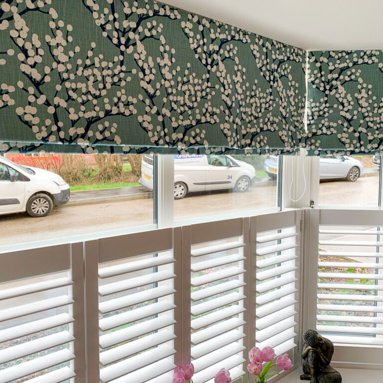 Green and blue floral print Roman blinds with cafe style shutters